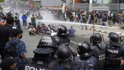 A polícia de tumultos usa canhão de água em manifestantes durante confrontos fora do parlamento em Katmandu, Nepal.