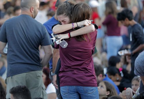 Students share an embrace at a memorial for the victims. (EPA/AAP)