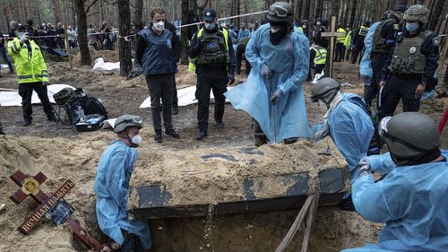 Emergency workers move a body during the exhumation in the recently retaken area of Izium, Ukraine, Friday, Sept. 16, 2022. 