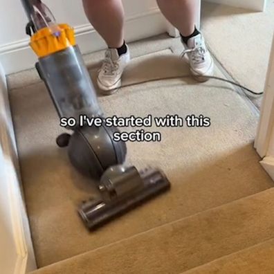 Woman uses carpet cleaner on floors before moving out of rental.
