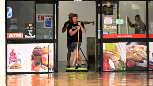 A man pushes water out of a flood-affected business on March 31, 2022 in Lismore, Australia. 
