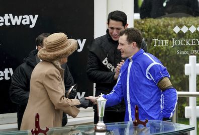 Jockey Paul Townend, right, shakes hands with Britain's Camilla, the Queen Consort after winning the Queen Mother Champion Chase aboard Energumene, on day two of the Cheltenham Festival at Cheltenham Racecourse, England, Wednesday March 15, 2023.