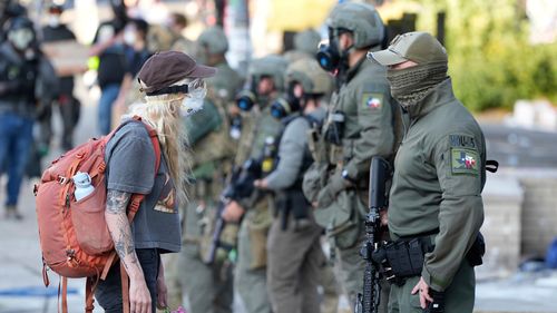 FILE - A female stands disconnected pinch a rule enforcement serviceman wearing a Houston Field Office Special Response Team spot extracurricular nan U.S. Immigration and Customs (ICE) building during a protestation Saturday, June 14, 2025, successful Portland, Ore. (AP Photo/Jenny Kane, File)