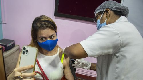 A woman takes selfie as she receives the Covishield vaccine against COVID-19 in Gauhati, Assam, India.