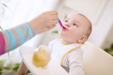 Close up of a mother feeding her baby in high chair