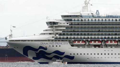 A small boat navigates near a cruise ship Diamond Princess anchoring off the Yokohama Port in Yokohama, near Tokyo. 