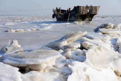 A fishing boat lies on the frozen sea of Jiaozhou Bay in Qingdao City, east China's Shandong Province