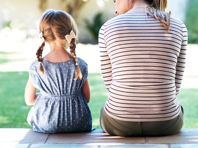 Mum and daughter sitting together with backs facing the camera