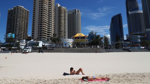 People lie on the beach at Surfers Paradise beach in Gold Coast, Australia.