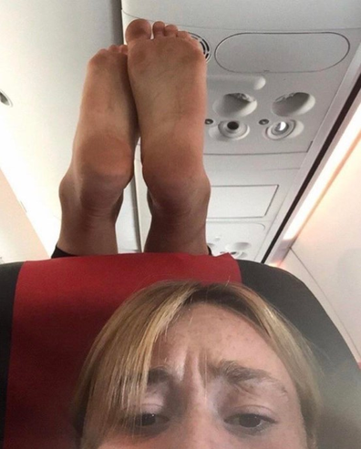 Plane passenger puts dirty feet on woman's headrest