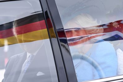 King Charles III, left, and Camilla, the Queen Consort, right, drive in a car after they arrived at the airport in Berlin, Wednesday, March 29, 2023. 