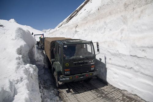 An Indian army trucks carrying supplies for soldiers drive past walls of snow on the Zojila Pass, northeast of Srinagar, Indian controlled Kashmir.