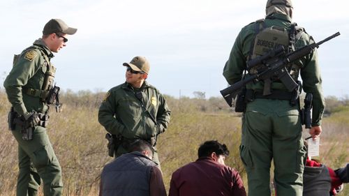 US border agents in Texas  hold suspected migrants who made an unauthorised crossing from Mexico.