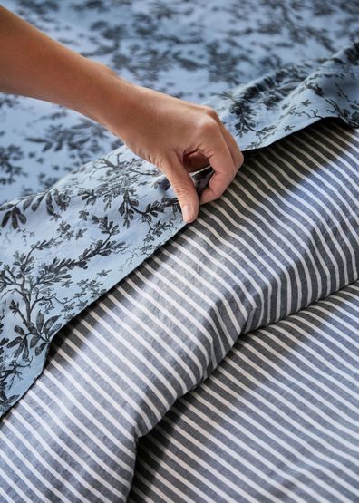 Floral bed sheet paired with a striped bed sheet.
