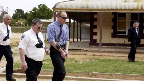File photo from 2002 of accused murderer Robert Joe Wagner is escorted handcuffed by a court sherriff outside the house 25 Railway Tce in Snowtown.