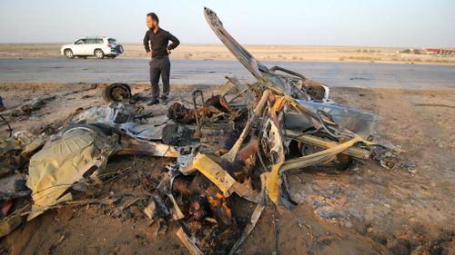 An Iraqi man inspects a wrecked vehicle after Daesh carried out a terror attack with a bomb-laden vehicle following the attack to a restaurant. (AFP)