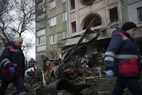 Workers pass the scene where a helicopter crashed on civil infrastructure in Brovary, on the outskirts of Kyiv, Ukraine, Wednesday, Jan. 18, 2023 