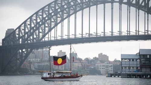 A boat flying the Aboriginal under the Sydney Harbour Bridge on January 26, 2020.