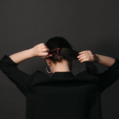 Woman tying hair up in ponytail