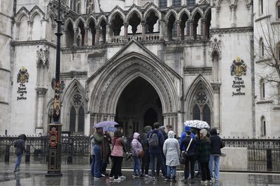People stand outside the Royal Court of Justice in London, Friday, March 17, 2023