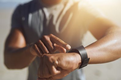 Closeup shot of a man checking his smartwatch while exercising outdoors.