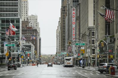 Pedestrians walk a mostly empty Sixth Avenue during the coronavirus outbreak, Friday, April 3, 2020, in New York