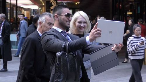 Salim takes a selfie with a passer-by outside court. Picture: 9News