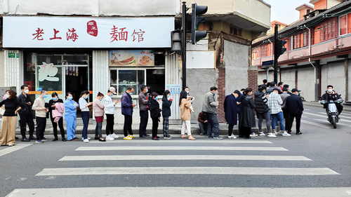 2022년 3월 11일 금요일 상하이의 한 병원에서 주민들이 COVID-19 검사를 받기 위해 길가에 있는 국수 가게 근처에 줄을 서고 있습니다. 