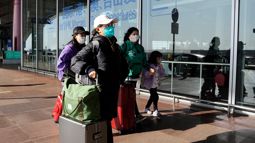 Passengers wearing masks walk through the Capital airport terminal in Beijing on Dec. 13, 2022.