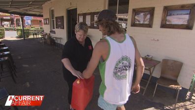 Trangie cafe owner Julie receiving a jerry can from fellow local Alex.
