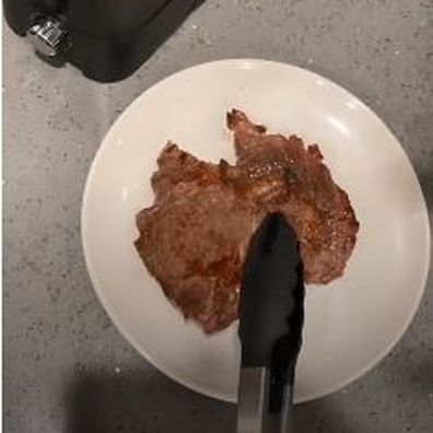 Woman cooks steak in a toaster