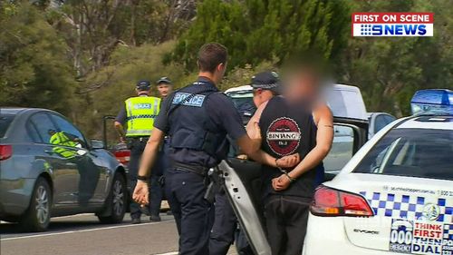 Two men were taken away in handcuffs but one was later released without charge. (9NEWS)