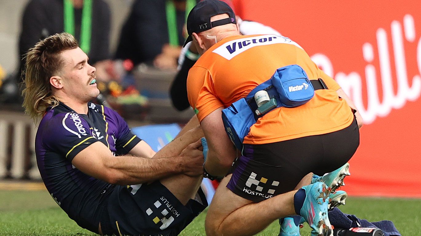 Ryan Papenhuyzen of the Storm is checked over by a trainer after copping an injury against the Dragons.
