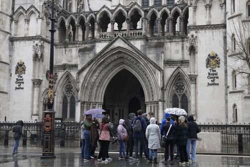 Des gens se tiennent devant la Royal Court of Justice de Londres, le vendredi 17 mars 2023
