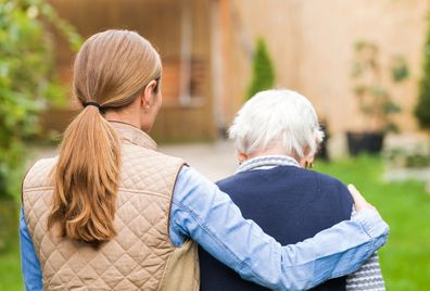 Young caregiver walks with the elderly woman in the park
