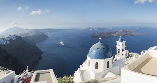 Early morning view in Santorini of the Imerovigli church sitting on top of the volcanic caldera. Santorini in Greece is one of the most famous travel destination in the World with numerous cruise ships anchoring in the bay below. The architecture is also famous for the duotone colors of the white painted buildings and light blue details.