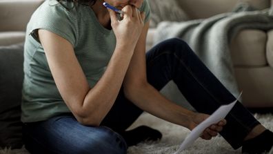 Woman pay bills sitting on floor at home