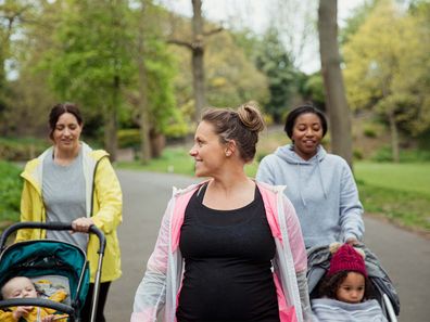 Two mums with kids in strollers and a pregnant woman walking.