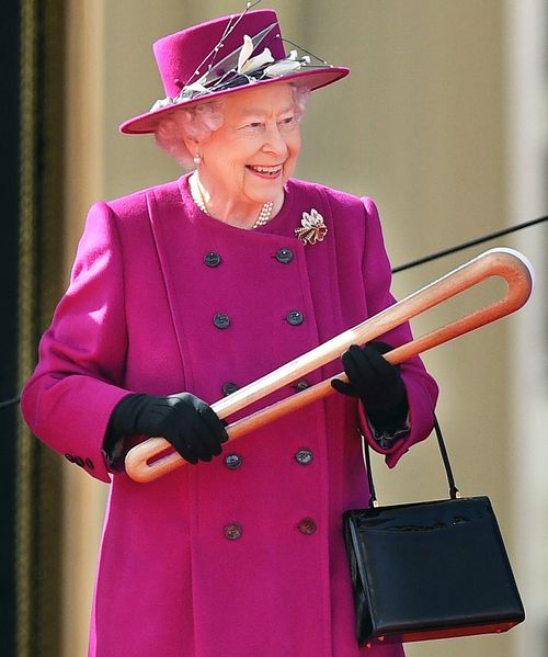 The Queen holds the baton at the relay ceremony at Buckingham Palace. (AAP)