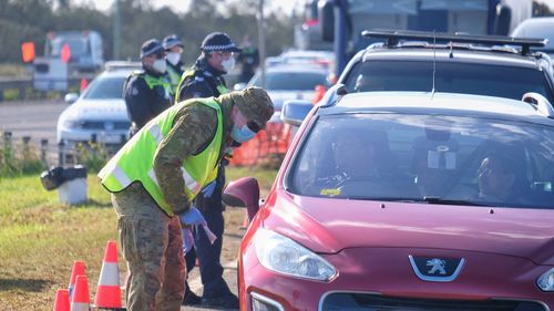 Members of the ADF and Victoria Police work together at a vehicle checkpoint along the Princes Freeway near Little River.