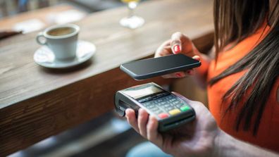 Woman at cafe scanning credit card