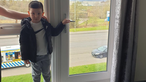 Kim Duncan's four-year-old son, Lewis, standing in front of the apartment's window-sized door.