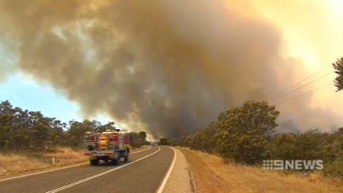 A fire truck races towards the plume of black smoke billowing from the fire. (9NEWS)