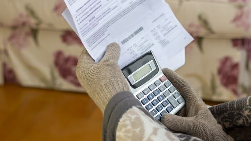 Uomo maturo preoccupato che legge la lettera di notifica di interruzione di corrente, tiene in mano la bolletta del riscaldamento, è confuso e stupito da notizie incredibili: fattura fiscale elevata, notifica di debito, cattivo rapporto finanziario, problema di soldi