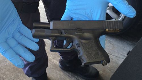 An officer presents a gun seized in the bust. (NSW Police)