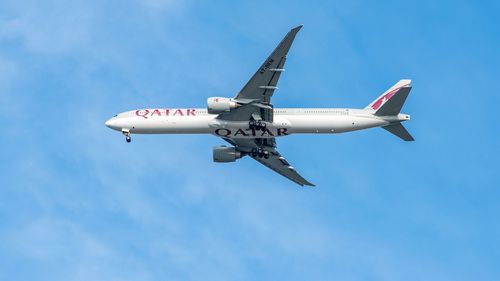 A Qatar Airways plane flies over Brisbane Airport