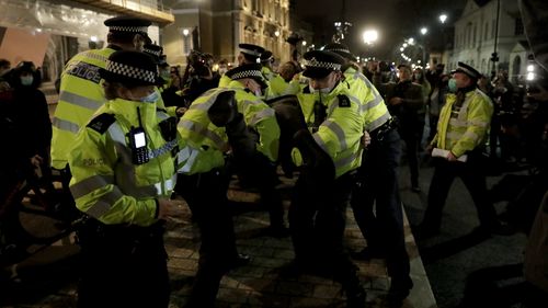 Police officers restrain a man after they were telling people to go home during a march to reflect on the murder of 33 year old marketing executive, Sarah Everard, in London, Monday, March 15, 2021. The British government is under pressure to do more to protect women and ensure the right to protest as Parliament prepares to debate a sweeping crime bill amid anger over the way police broke up a vigil for a young murder victim abducted on the streets of London. (AP Photo/Matt Dunham)