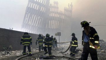 Firefighters work beneath the destroyed mullions, the vertical struts, of the World Trade Center in New York on Tuesday, Sept. 11, 2001.
