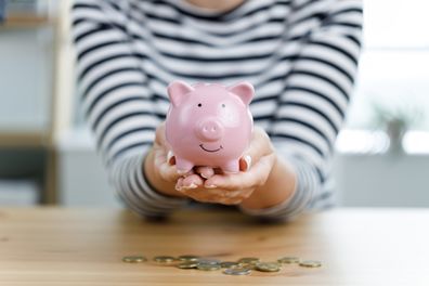 Woman hands holding piggy bank on wooden table. Saving money and financial investment