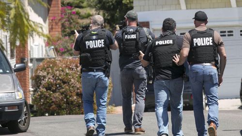 Heavily armed San Diego police officers approach a house thought to be the home of 19 year-old John T Earnest.